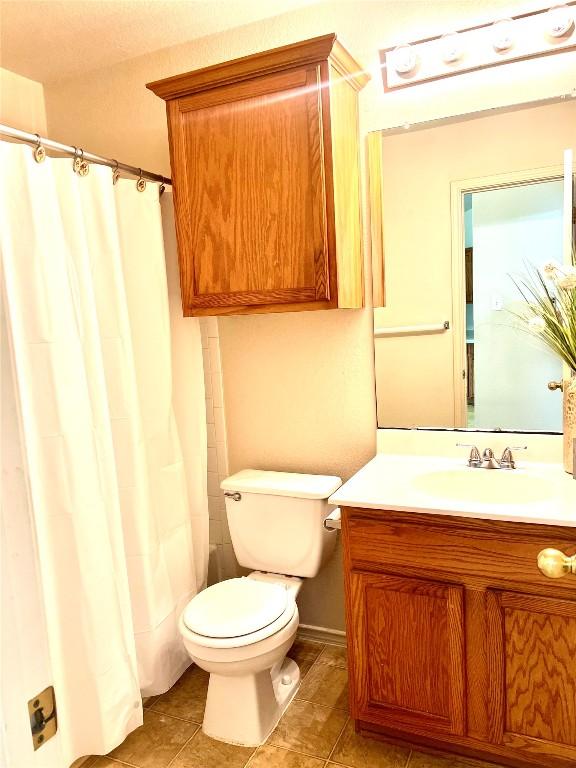 full bathroom featuring a shower with shower curtain, vanity, and toilet