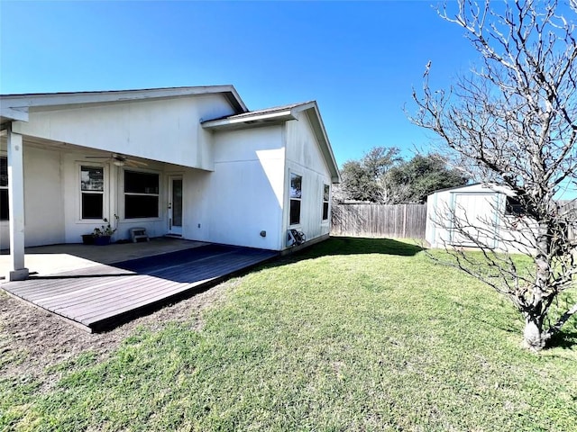 rear view of property with ceiling fan, a yard, a deck, and fence