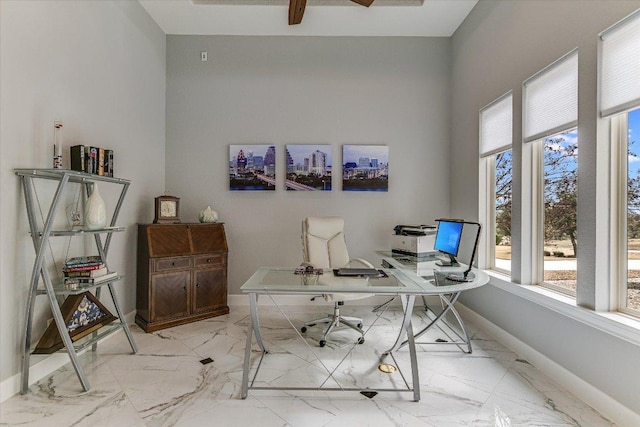 office featuring a towering ceiling, marble finish floor, and baseboards