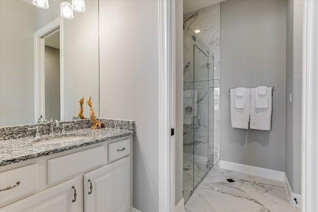 full bath with marble finish floor, a marble finish shower, vanity, and baseboards