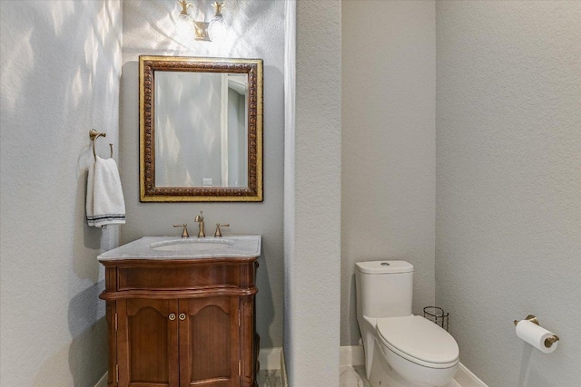 half bathroom featuring toilet, baseboards, and vanity