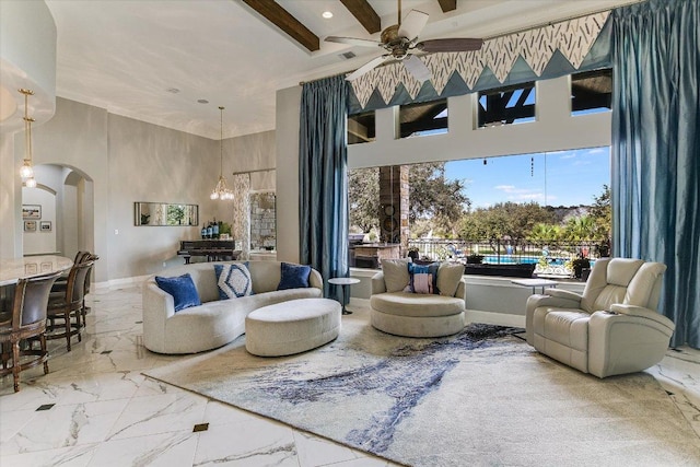 interior space featuring arched walkways, marble finish floor, beam ceiling, a towering ceiling, and ceiling fan with notable chandelier