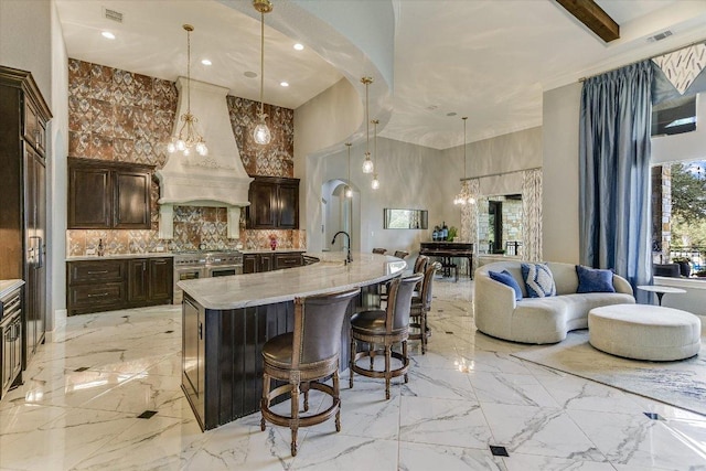 kitchen with range with two ovens, premium range hood, a towering ceiling, open floor plan, and marble finish floor