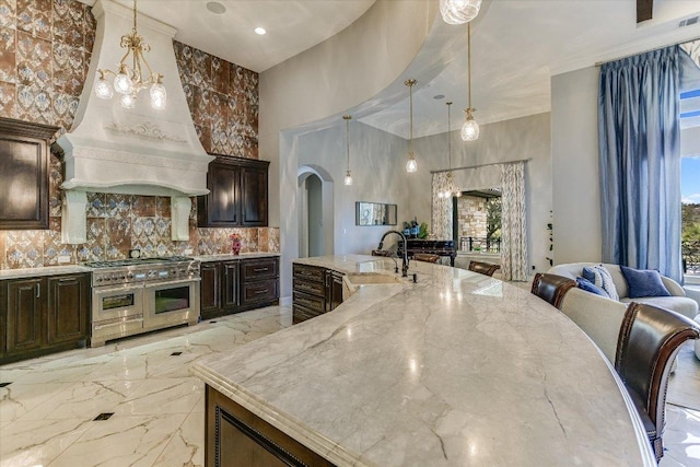 kitchen with arched walkways, marble finish floor, a sink, light stone countertops, and double oven range