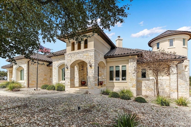 view of front of house with a chimney, a tile roof, and stucco siding