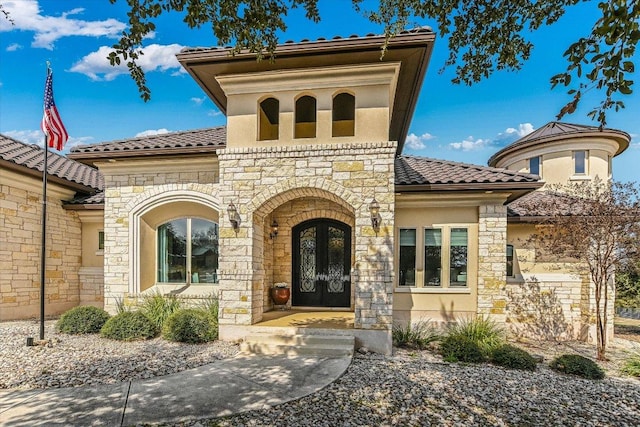 view of front of property featuring french doors, a tile roof, and stucco siding