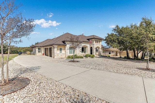 view of front of property featuring an attached garage, stone siding, concrete driveway, and a tile roof