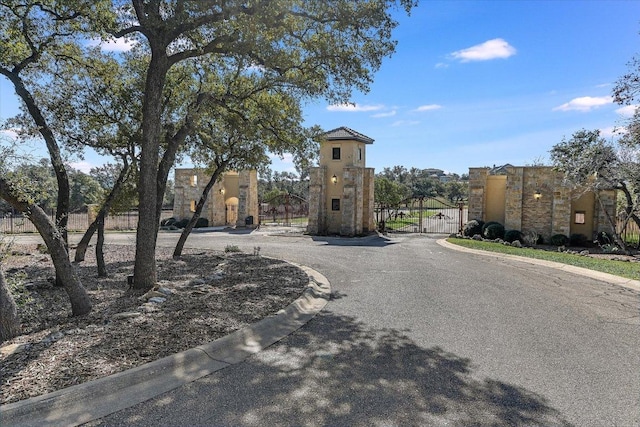 view of street featuring a gate, curbs, and a gated entry