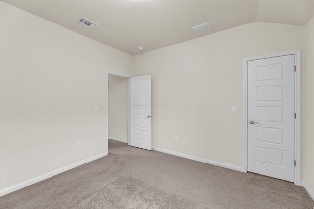 spare room featuring vaulted ceiling, carpet floors, visible vents, and baseboards