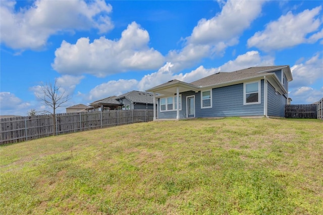 rear view of house with a fenced backyard and a yard