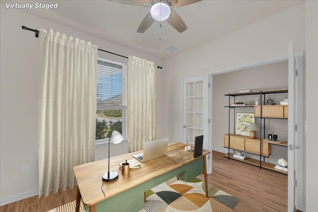 office space featuring baseboards, visible vents, a ceiling fan, and wood finished floors