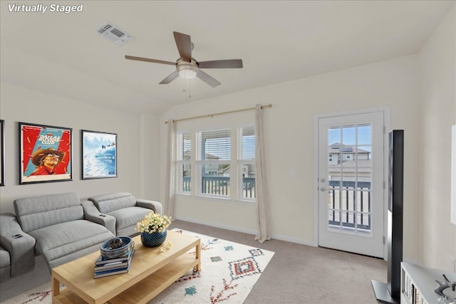 living room featuring light carpet, a wealth of natural light, lofted ceiling, and visible vents