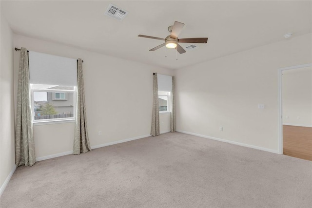 empty room with carpet floors, ceiling fan, visible vents, and baseboards