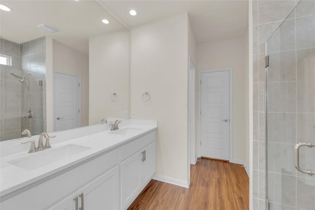 full bathroom featuring a sink, a shower stall, and wood finished floors