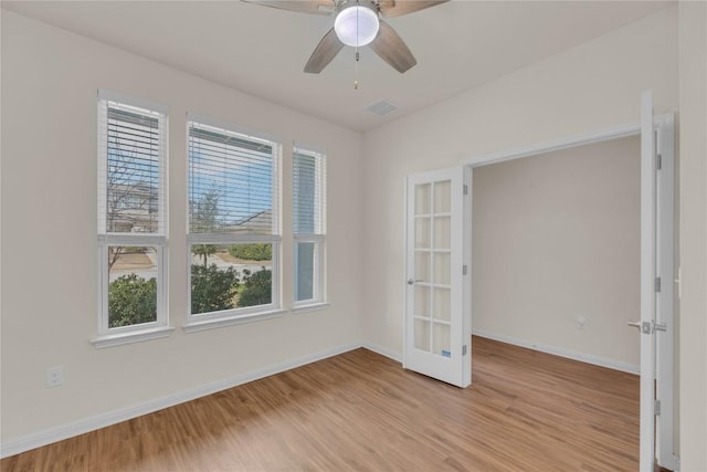 unfurnished room featuring light wood finished floors, baseboards, visible vents, and ceiling fan