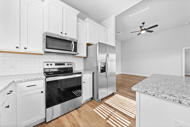 kitchen featuring light wood-style flooring, stainless steel appliances, a ceiling fan, white cabinets, and backsplash