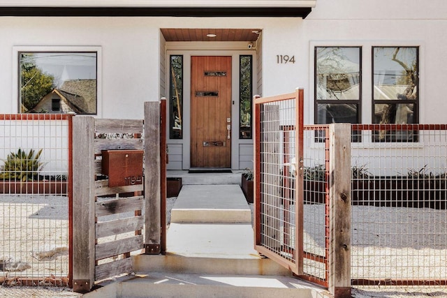 property entrance with fence and stucco siding