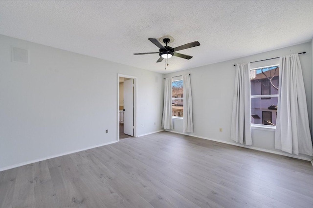 empty room with a ceiling fan, a textured ceiling, baseboards, and wood finished floors