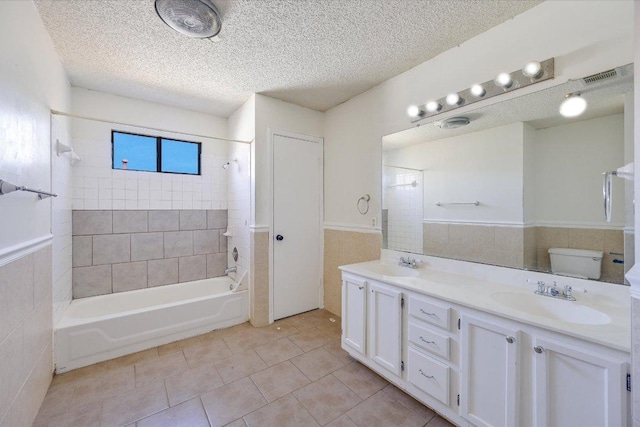 full bathroom featuring tub / shower combination, a sink, tile walls, and a textured ceiling