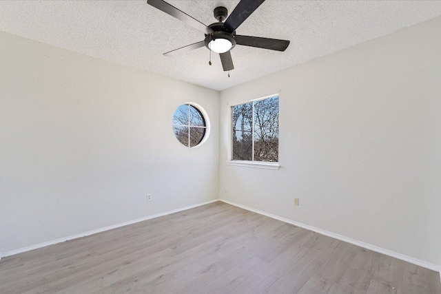 spare room featuring a ceiling fan, a textured ceiling, baseboards, and wood finished floors