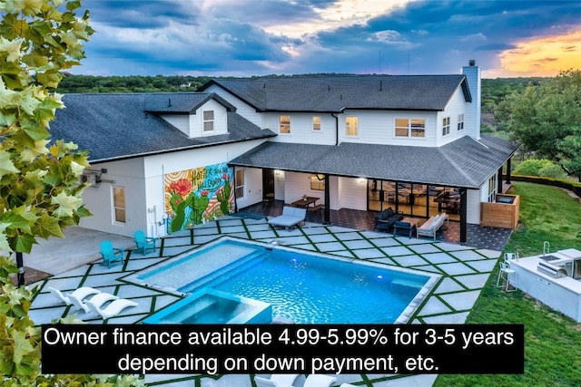 back of house at dusk with an outdoor pool, roof with shingles, and a patio