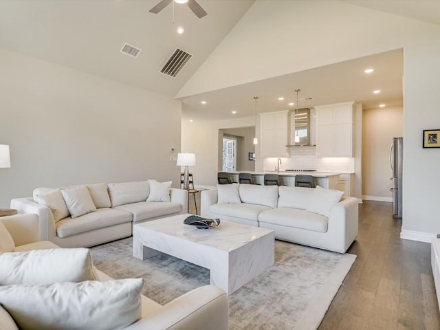 living room featuring baseboards, visible vents, wood finished floors, and recessed lighting