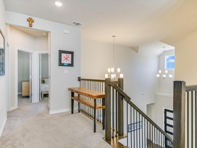 hall with carpet floors, a notable chandelier, visible vents, an upstairs landing, and baseboards