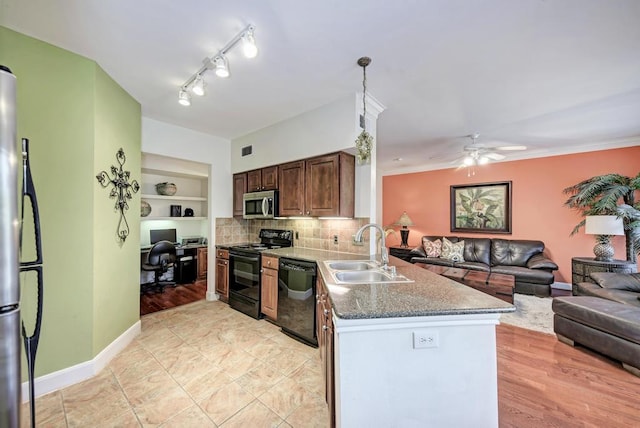 kitchen featuring built in shelves, open floor plan, a sink, a peninsula, and black appliances