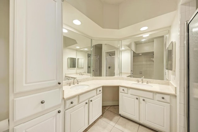 full bathroom with double vanity, a stall shower, a sink, and tile patterned floors