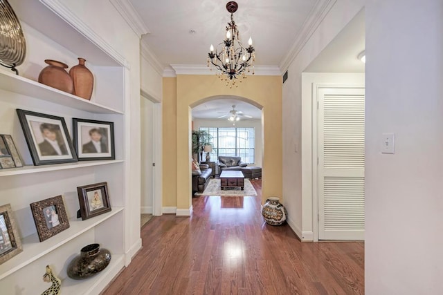 hallway with arched walkways, wood finished floors, visible vents, baseboards, and ornamental molding