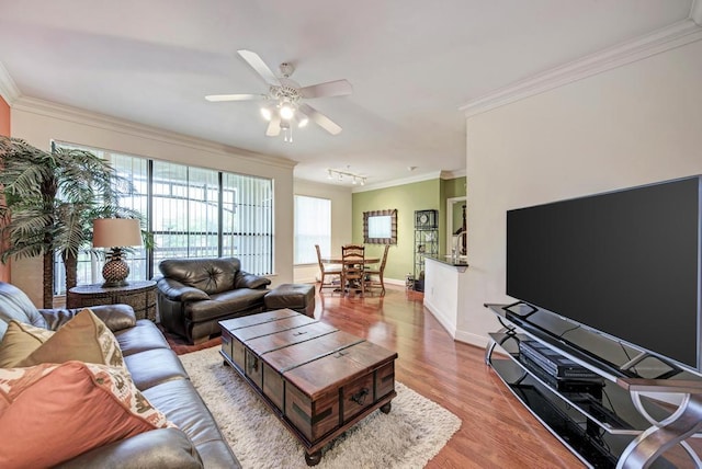 living area featuring baseboards, ceiling fan, ornamental molding, and wood finished floors