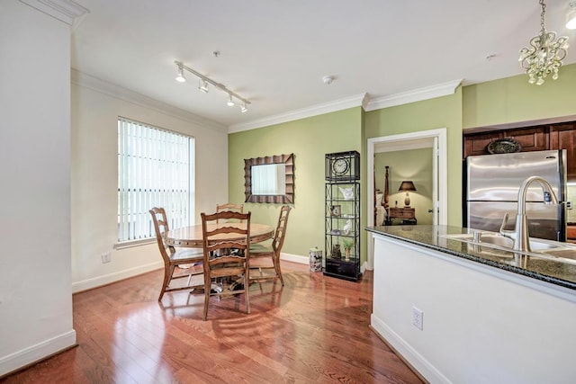 dining space with ornamental molding, baseboards, and wood finished floors