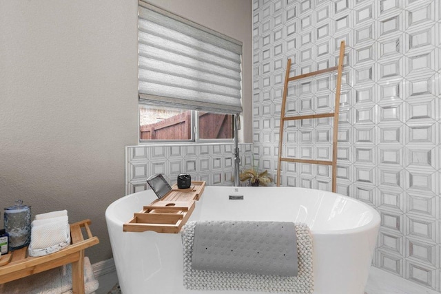 bathroom featuring a freestanding tub and tile walls