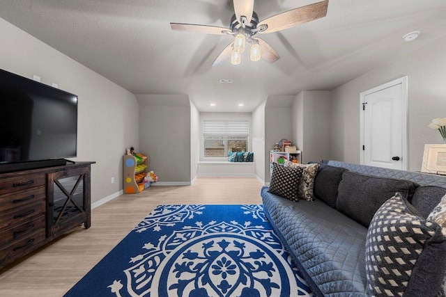 living area featuring a ceiling fan, visible vents, light wood-style flooring, and baseboards