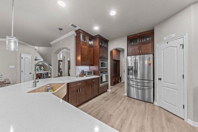 kitchen with arched walkways, a sink, visible vents, light countertops, and appliances with stainless steel finishes