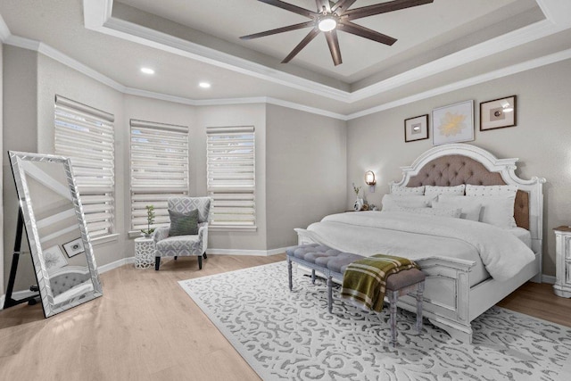 bedroom with wood finished floors, a raised ceiling, and baseboards