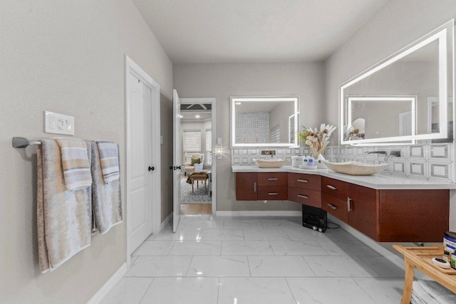 bathroom featuring marble finish floor, double vanity, a sink, and baseboards