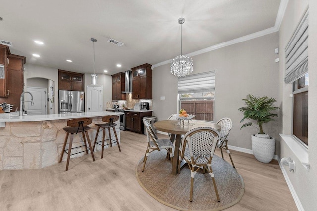 dining area featuring arched walkways, baseboards, visible vents, and light wood finished floors