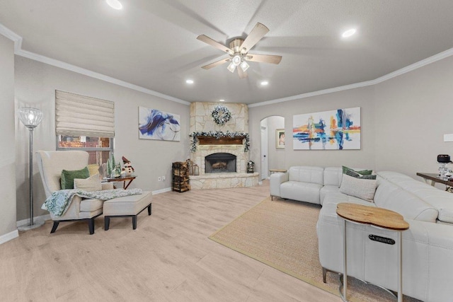 living room with ornamental molding, wood finished floors, and a stone fireplace