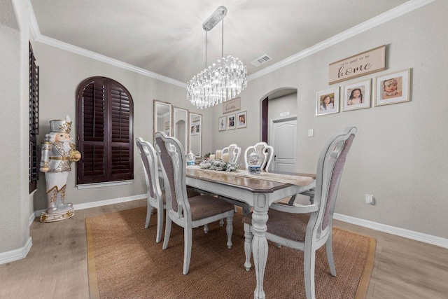 dining room featuring baseboards, wood finished floors, visible vents, and crown molding