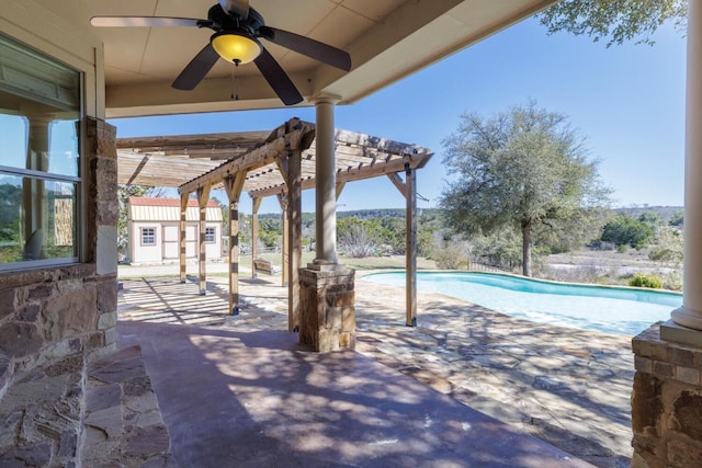 view of patio / terrace featuring ceiling fan, an outbuilding, an outdoor pool, and a pergola