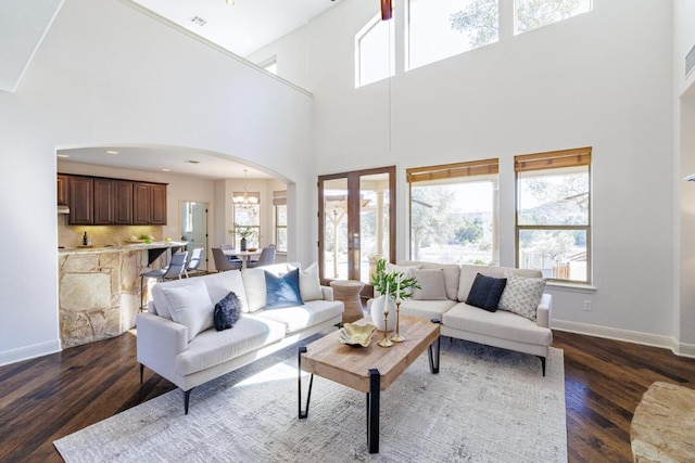 living area with a notable chandelier, dark wood-type flooring, and a healthy amount of sunlight