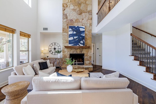 living room featuring baseboards, visible vents, dark wood-type flooring, stairs, and a fireplace