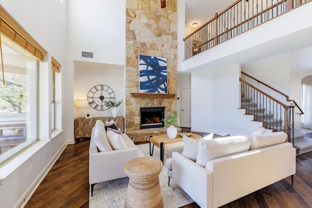 living room featuring a fireplace, dark wood finished floors, visible vents, and baseboards