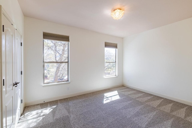 unfurnished room featuring light carpet and baseboards