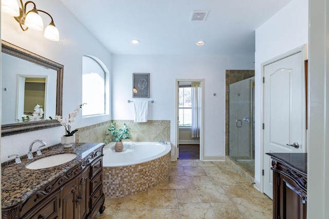 bathroom featuring visible vents, vanity, baseboards, a bath, and a stall shower