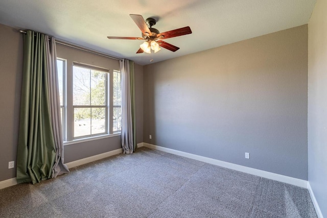 carpeted spare room featuring ceiling fan and baseboards