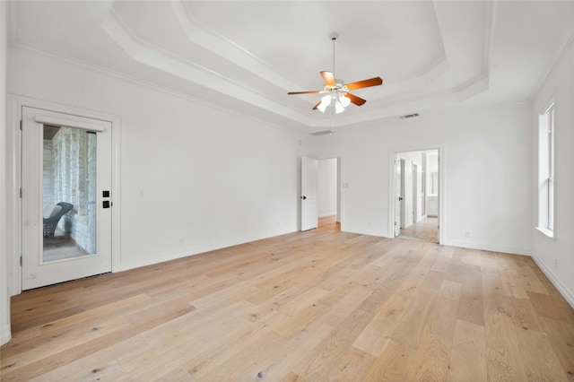 unfurnished room with light wood-style flooring, a tray ceiling, and crown molding