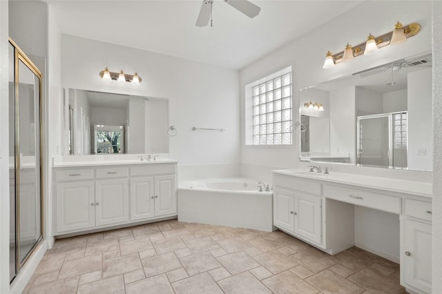 bathroom with a garden tub, a shower stall, two vanities, and a sink