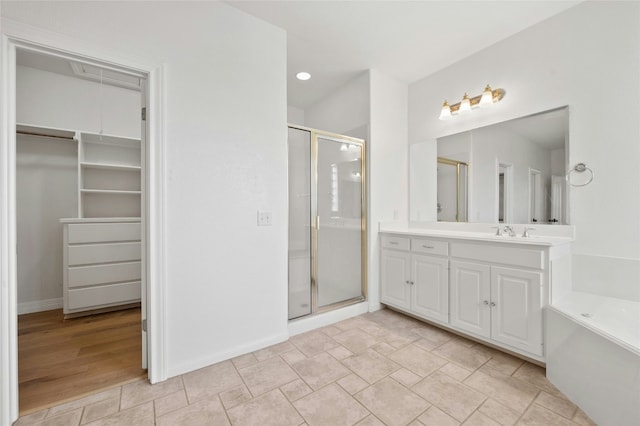 bathroom with a shower stall, a walk in closet, and vanity